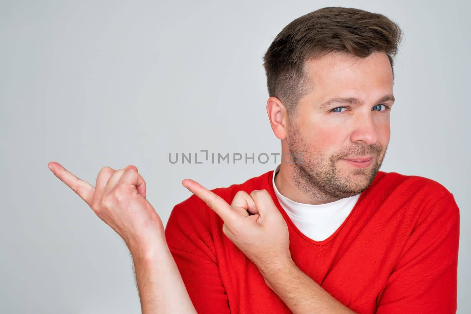 Positive mature caucasian man pointing aside giving advice isolated over white wall background. 