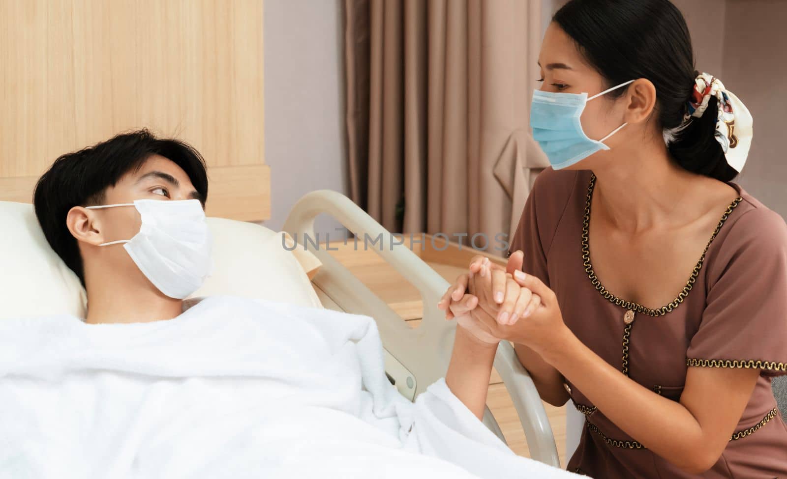 Young patient with attentive visitor and family holding hands in hospital sterile recovery room. The concept of family support for patients receiving hospital care. In-ward medical care and healthcare