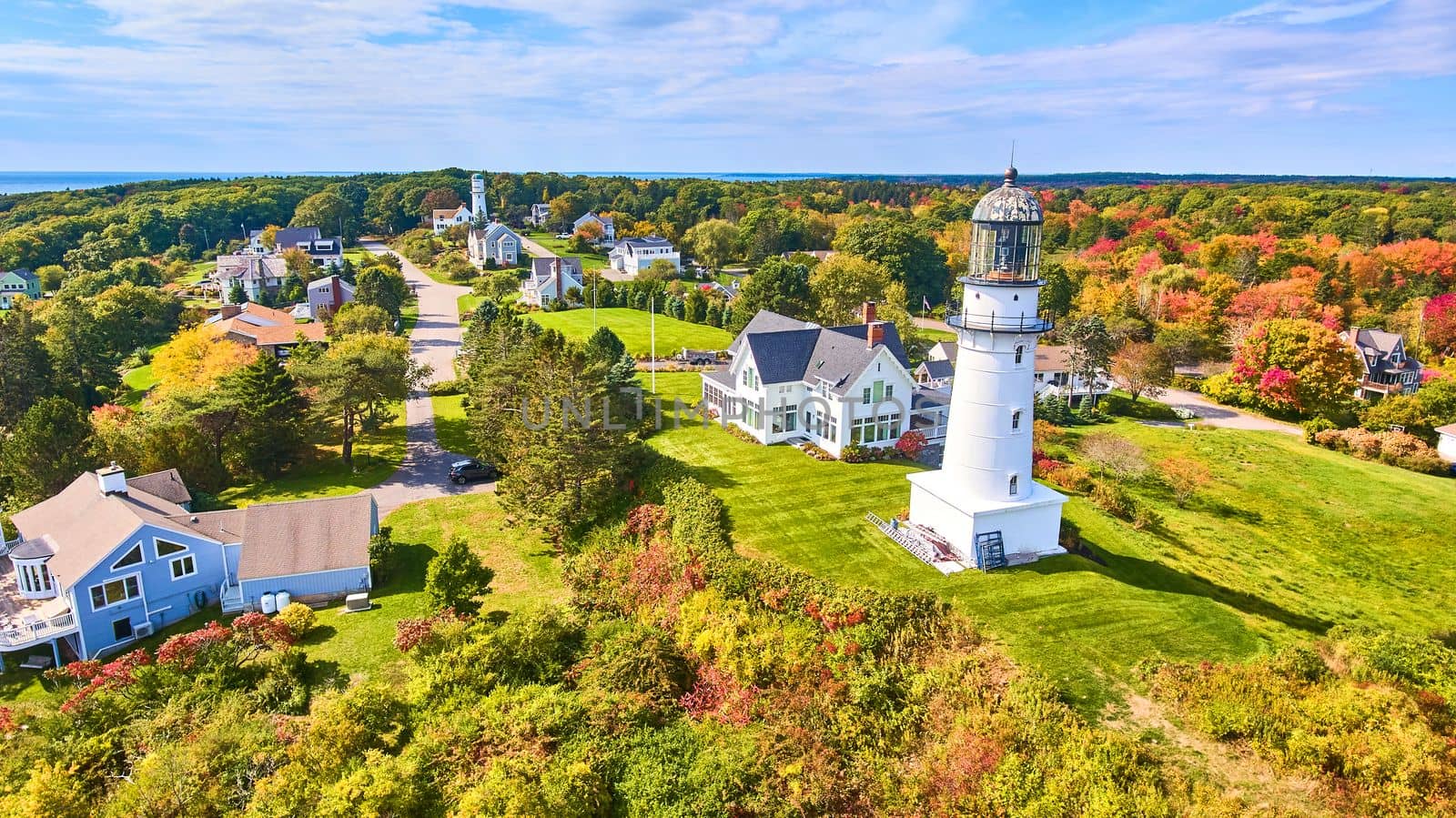 Image of Stunning pair of lighthouses in fall forest with homes surrounding