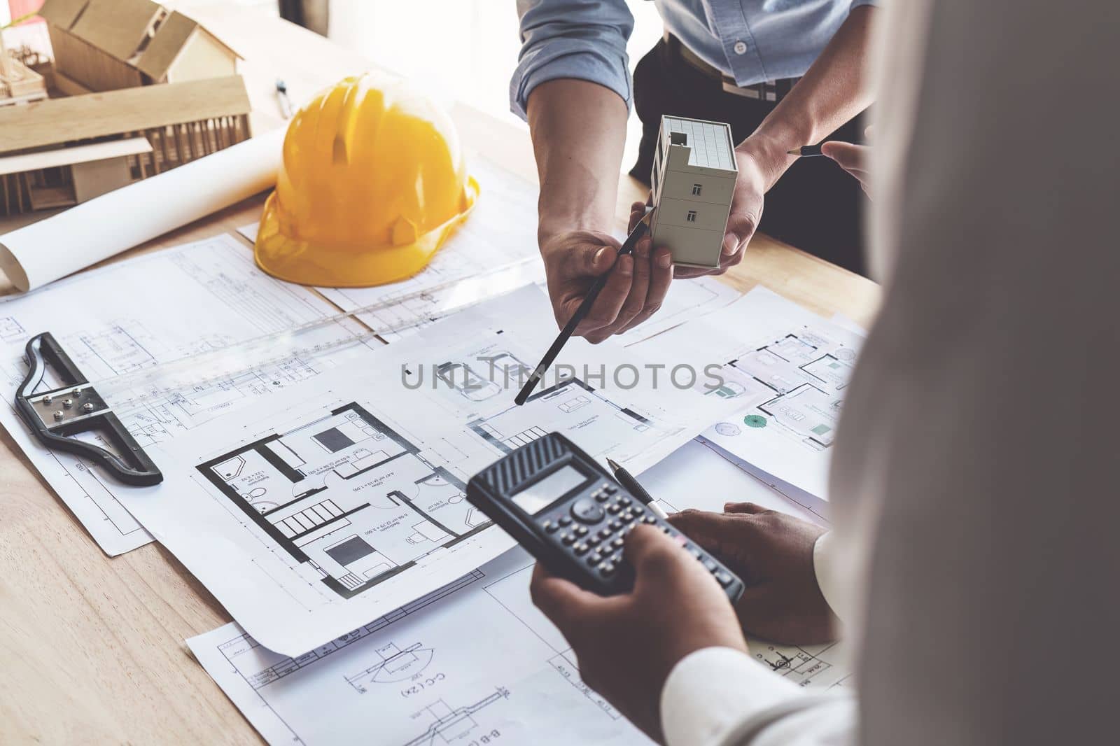 Architect team working with blueprints for architectural plan, engineer sketching a construction project, green energy concept.