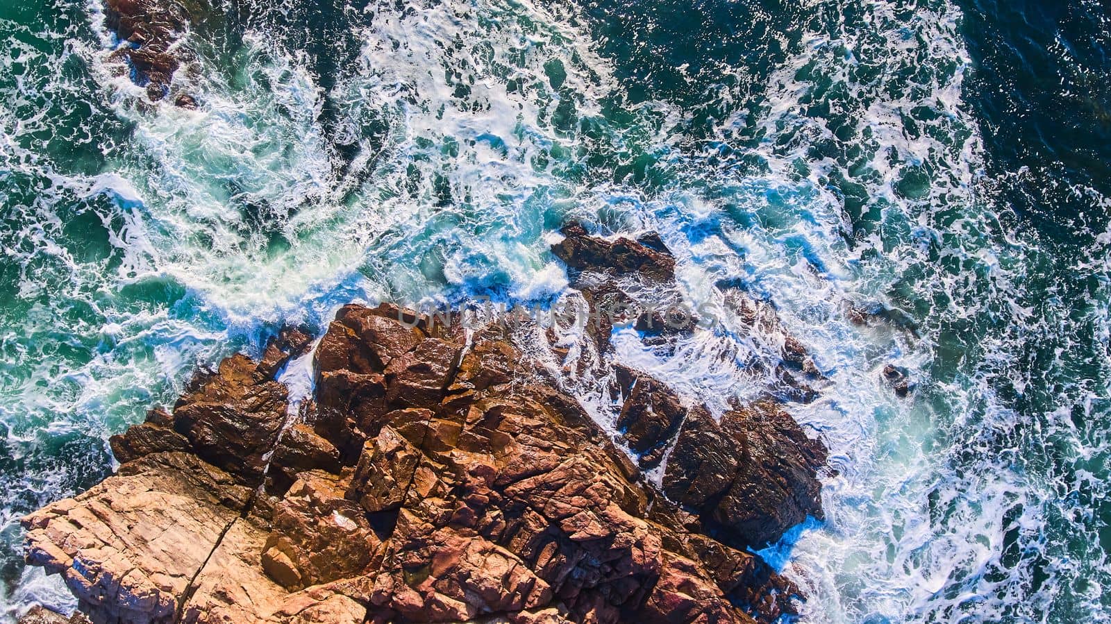 Image of Waves crashing into rocky coasts of Maine aerial from above looking down