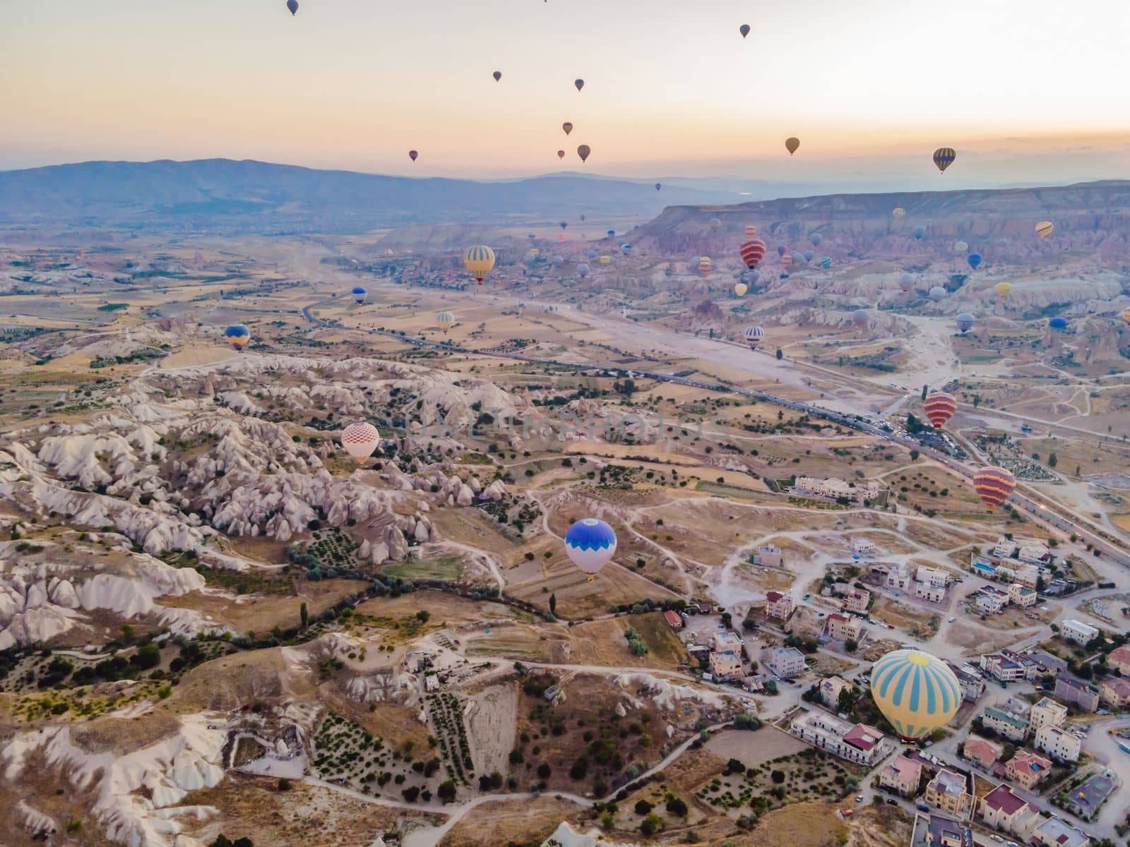 Colorful hot air balloons flying over at fairy chimneys valley in Nevsehir, Goreme, Cappadocia Turkey. Spectacular panoramic drone view of the underground city and ballooning tourism. High quality by galitskaya