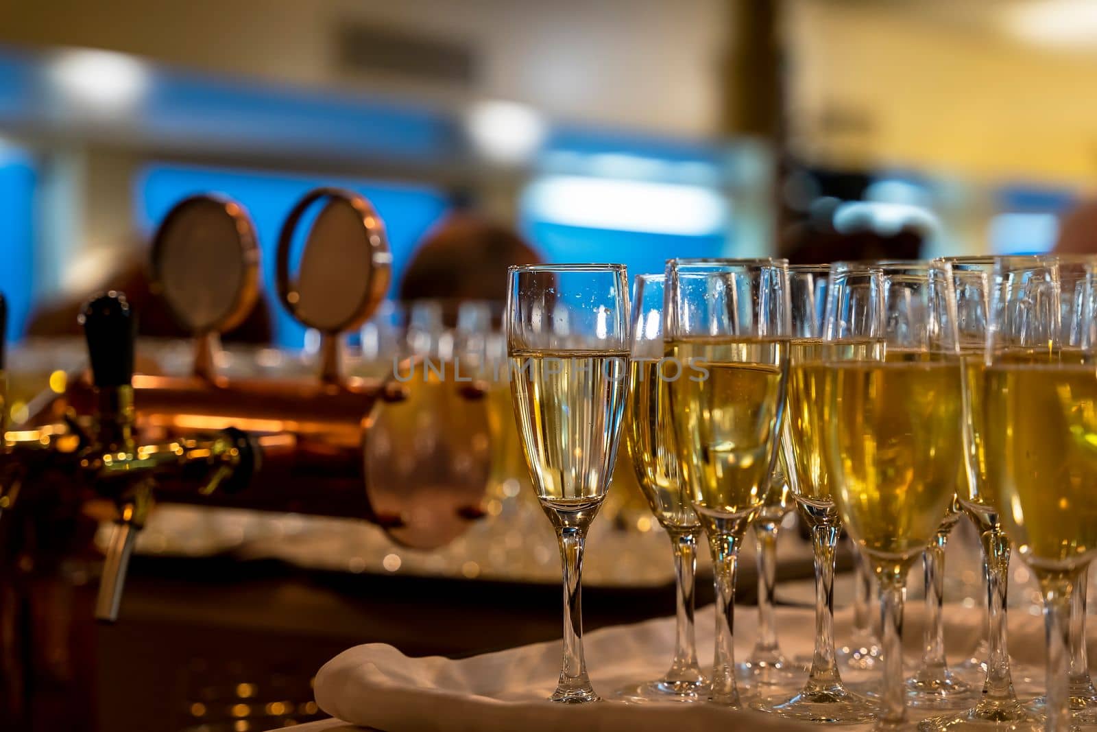 many beautiful glasses of champagne during a party on the table in the bar. close-up. glasses with cool champagne or white wine stand in rows on the bar counter, soft focus.