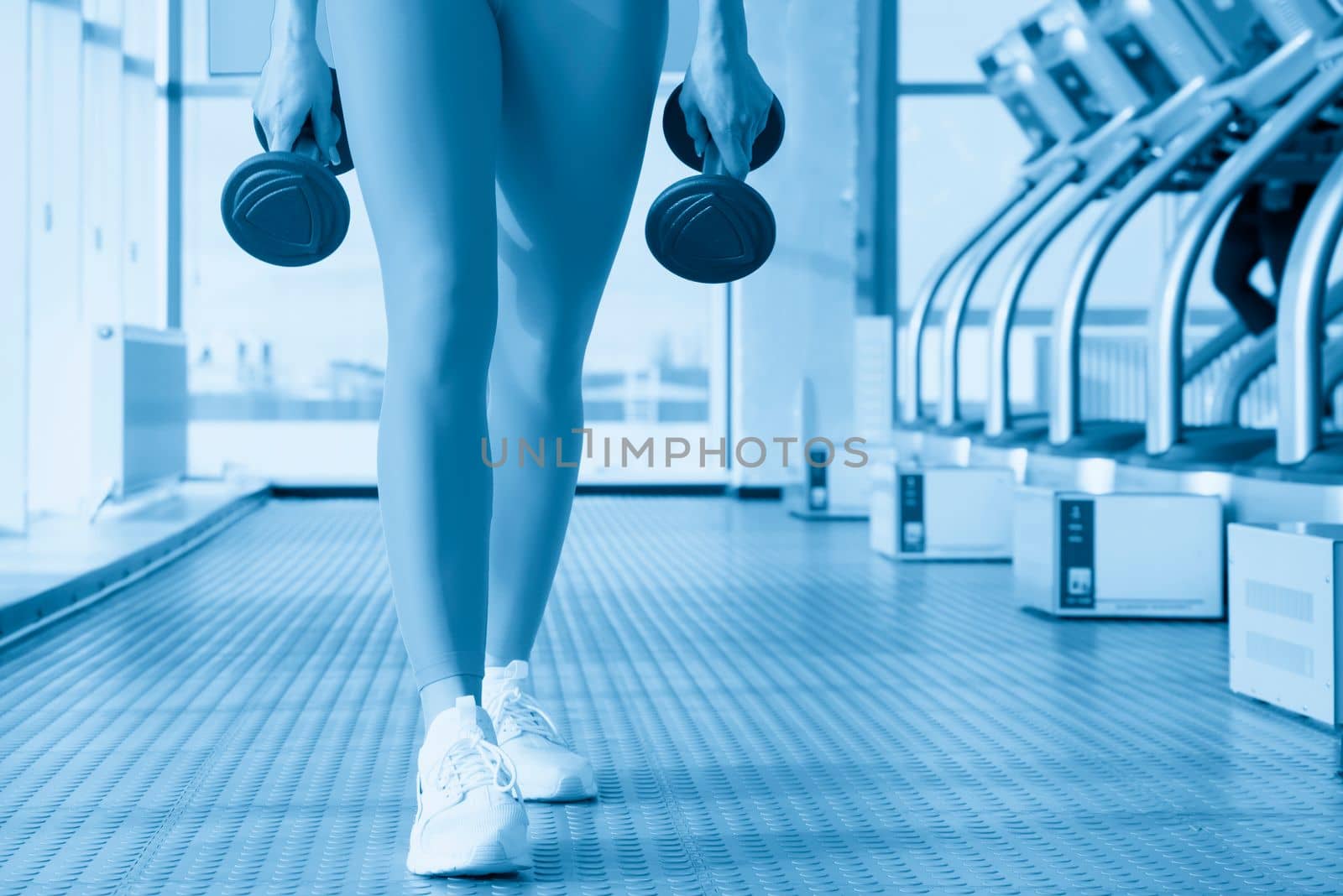 Young fitness woman working out with dumbbell in gym, sport concept by Mariakray