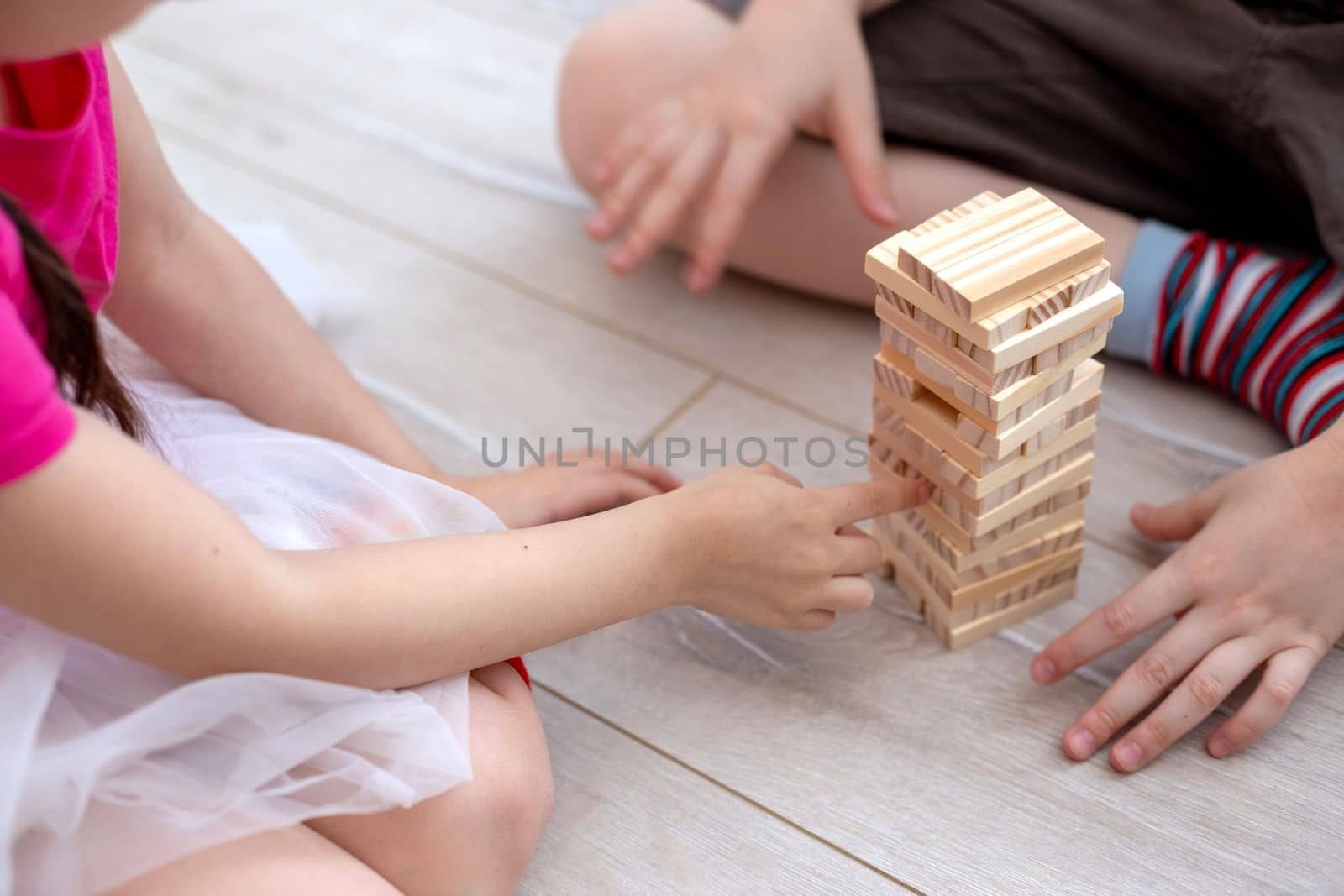 Childrens hands collects a tower of wooden blocks on the floor. by Zakharova