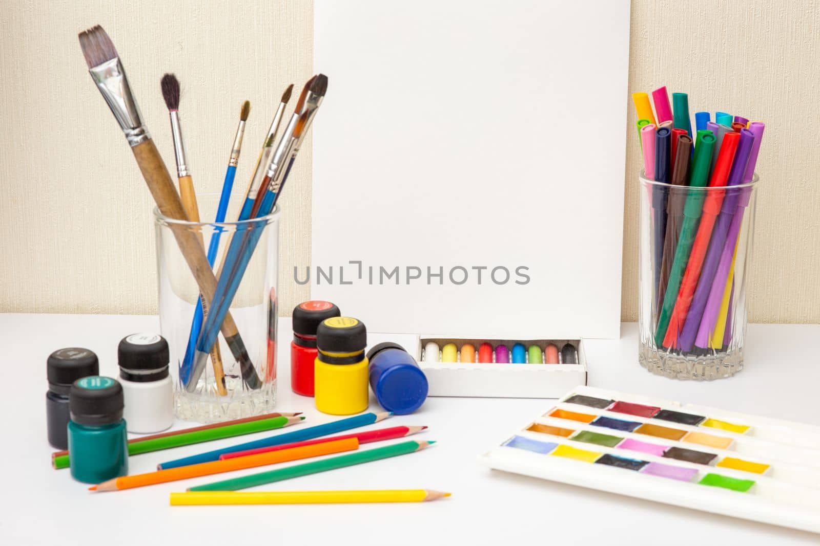 Paintbrushes and colorful drawing supplies on white table: watercolors,pastel crayons, pencils , acrylic paints. Mock up