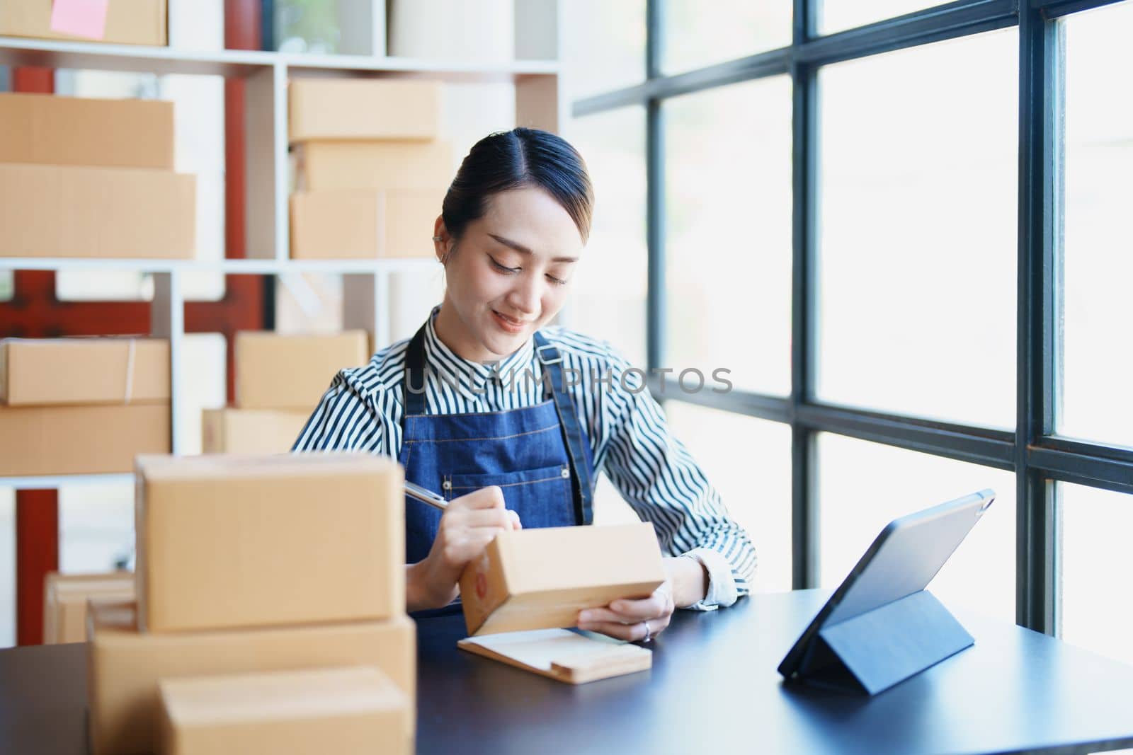 Starting small business entrepreneur of independent Asian female online seller packing products to send to customers and SME delivery concept by Manastrong