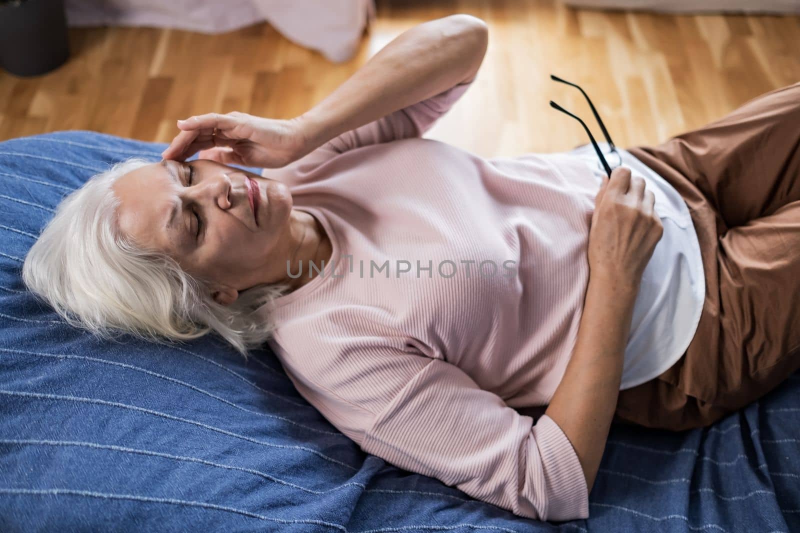 Senior caucasian woman suffering from a headache resting at home on sofa