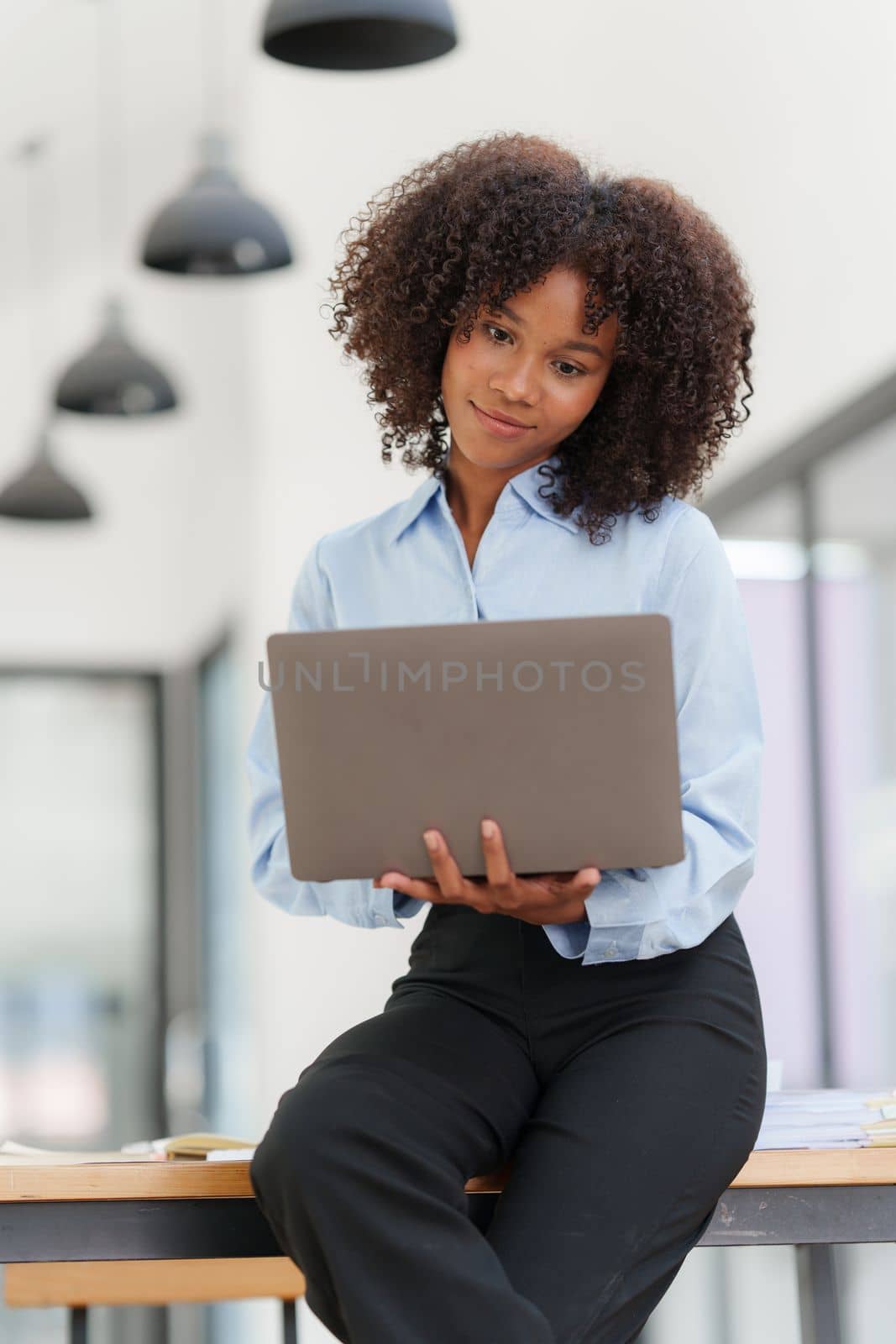 Portrait young african american businesswoman looking at laptop. Woman reading news, report or email. Online problem, finance mistake, troubleshooting.