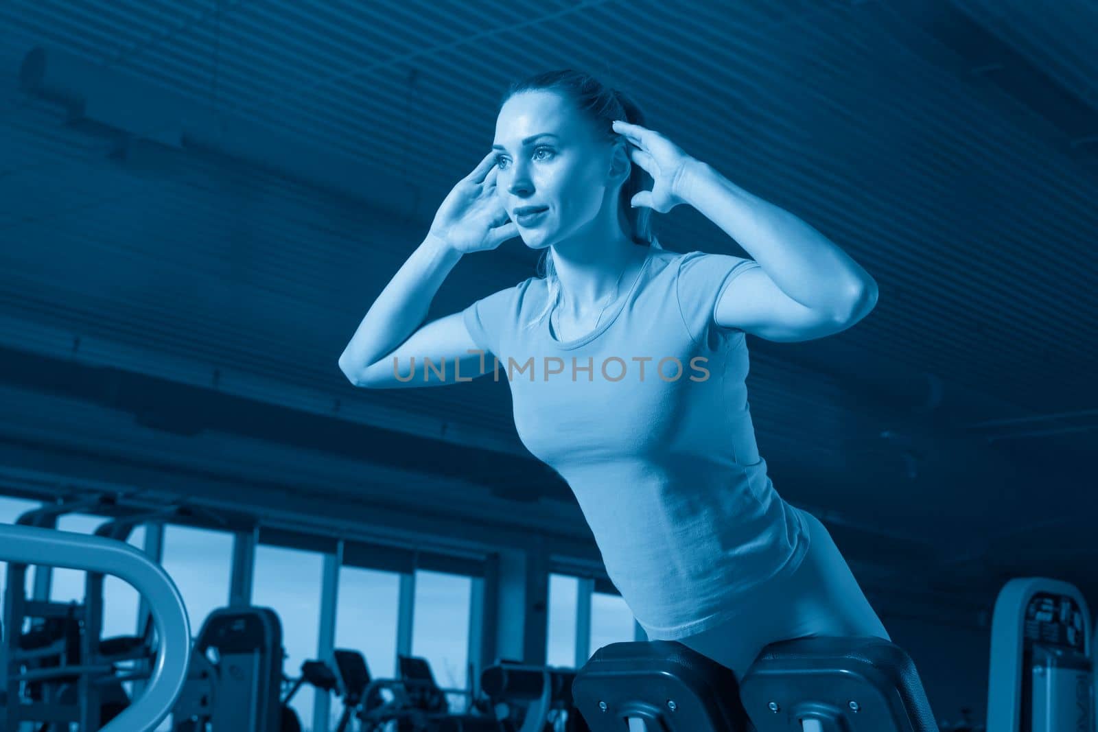 Young woman doing exercises on abs machine in gym by Mariakray