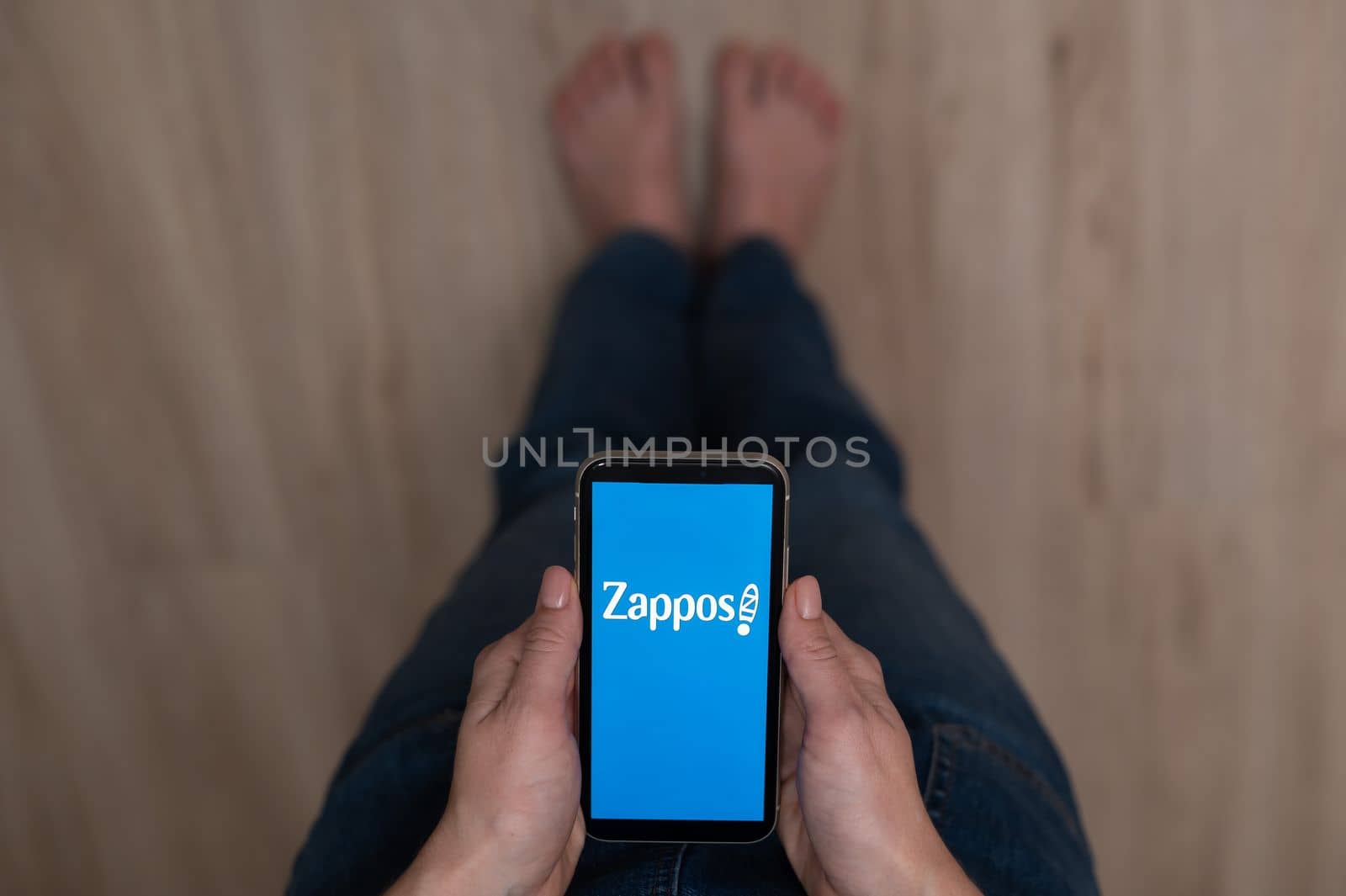 December 3, 2022 Almaty Kazakhstan: Barefoot woman holding smartphone with zappos logo. by mrwed54