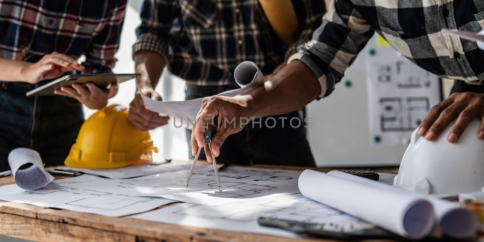 Architect team working with blueprints for architectural plan, engineer sketching a construction project, green energy concept.