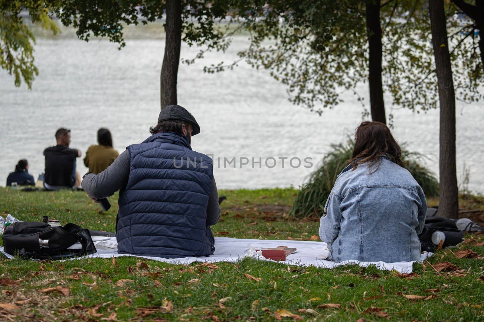 Couples relaxing on the grass in a park by the river and enjoying food. The concept of freedom and relaxation