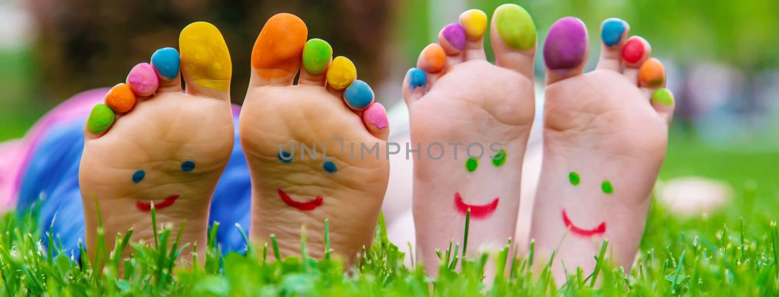 Children's feet with a pattern of paints smile on the green grass. Selective focus. by mila1784