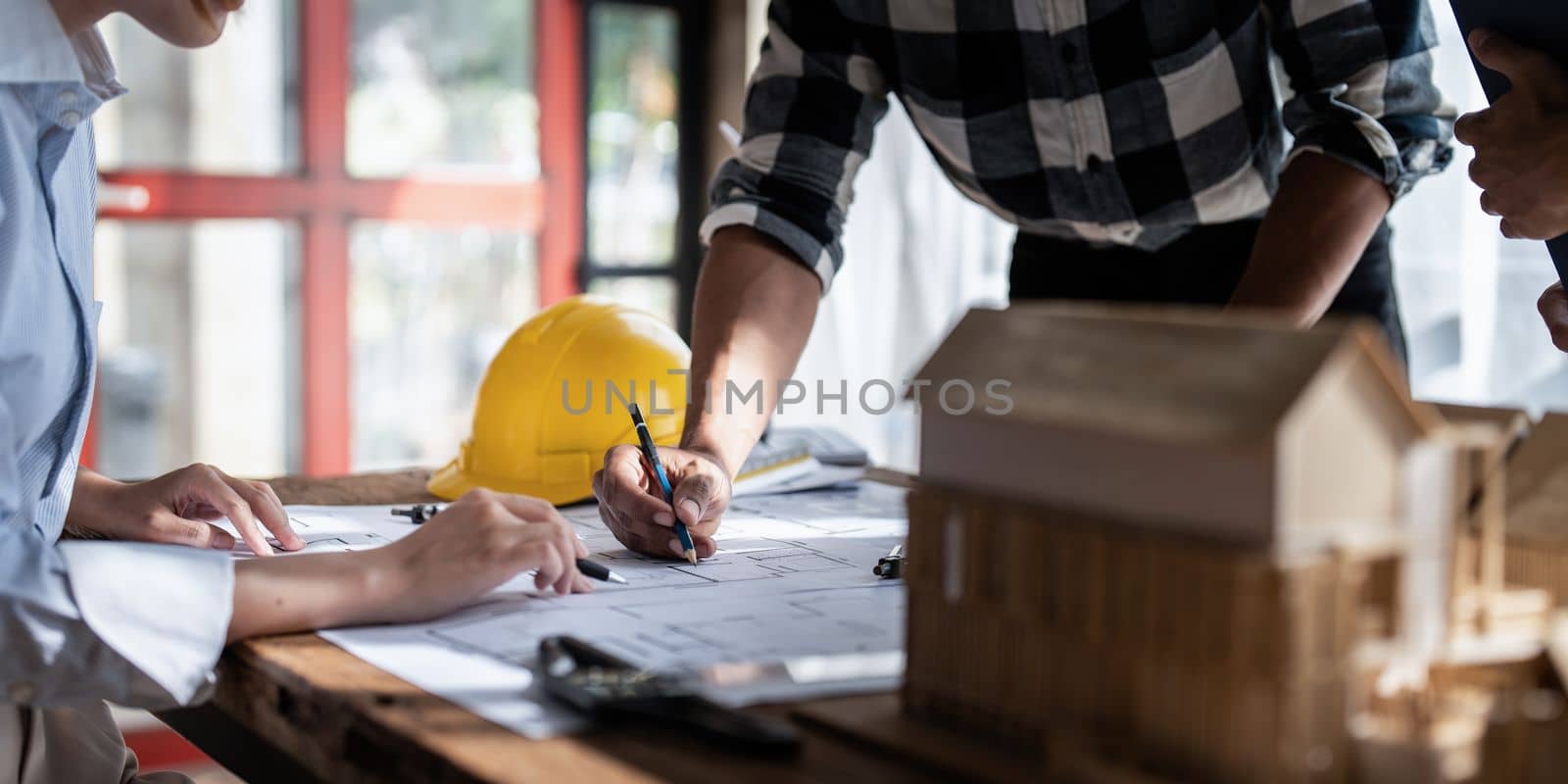 Architect team working with blueprints for architectural plan, engineer sketching a construction project, green energy concept.