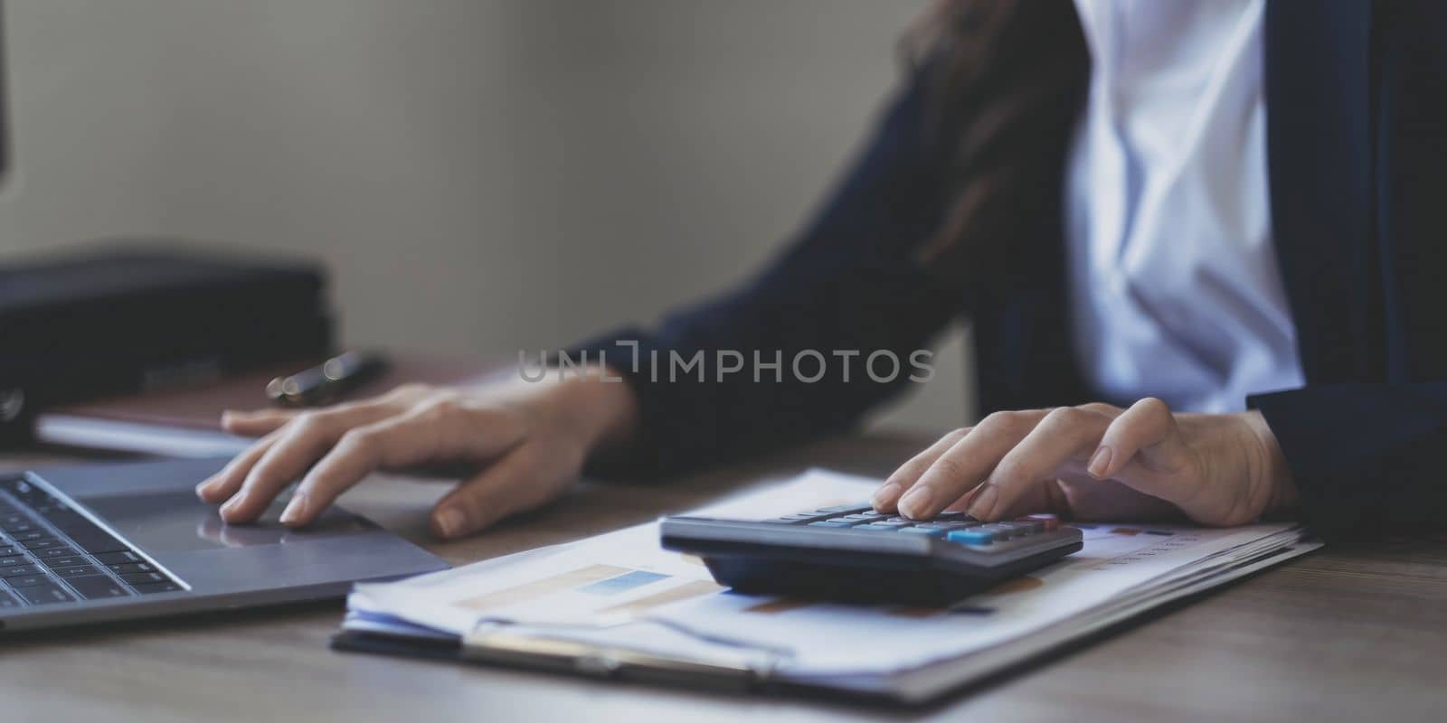 Close up .businesswoman or lawyer or accountant working on accounts using a smart phone laptop digital tablet calculator..