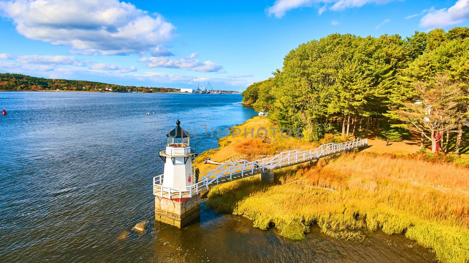 Aerial over small lighthouse in Maine with warm light by njproductions