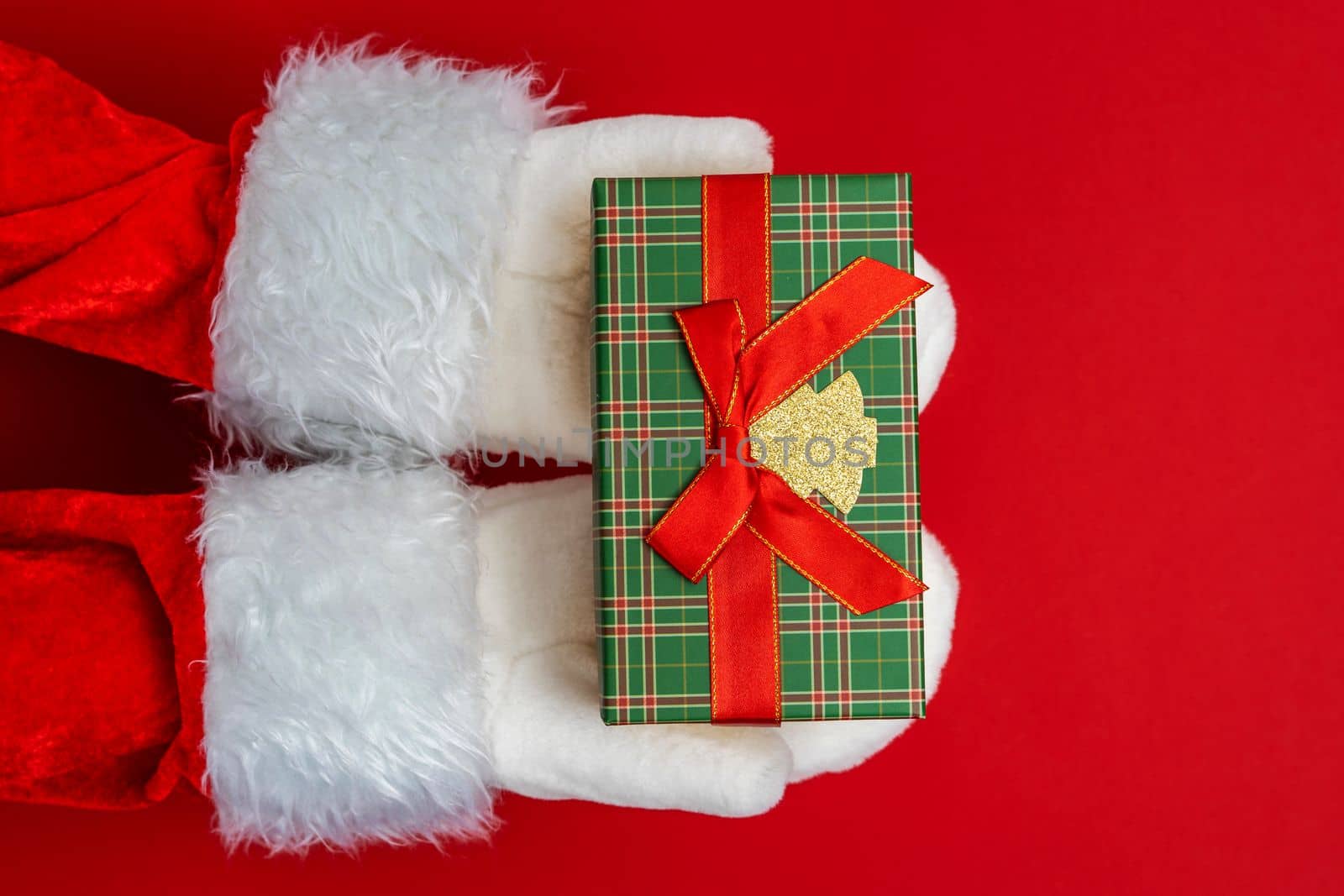 Santa's hands are holding a gift for Christmas. red background with space to copy. Christmas time