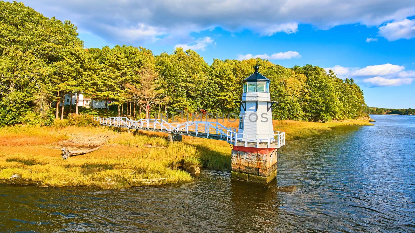 Image of Fall foliage on coast with small lighthouse in Maine and walkway