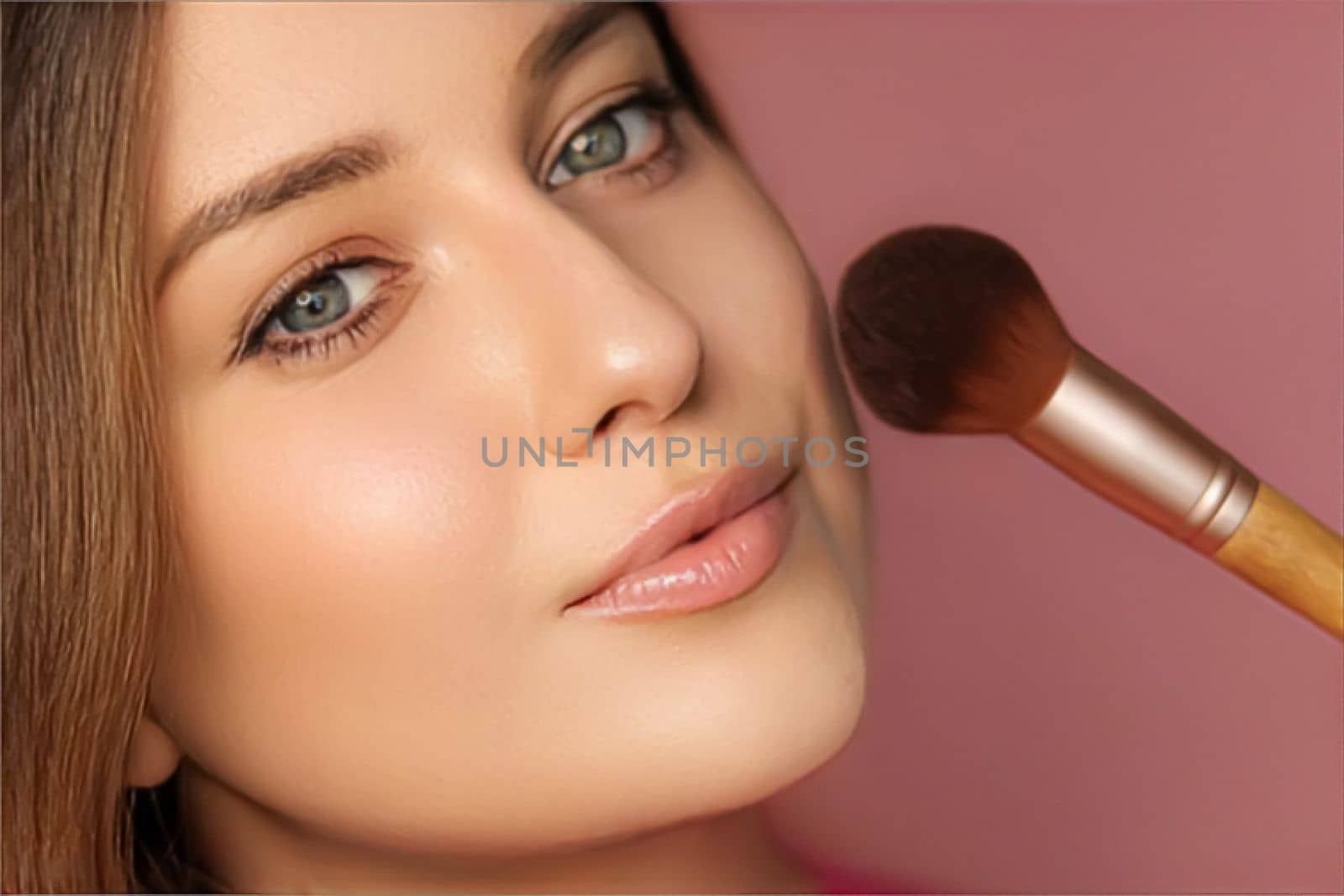 Beautiful young woman applying cosmetic powder product with make-up bamboo brush, beauty, makeup and skincare cosmetics model face portrait on pink background by Anneleven