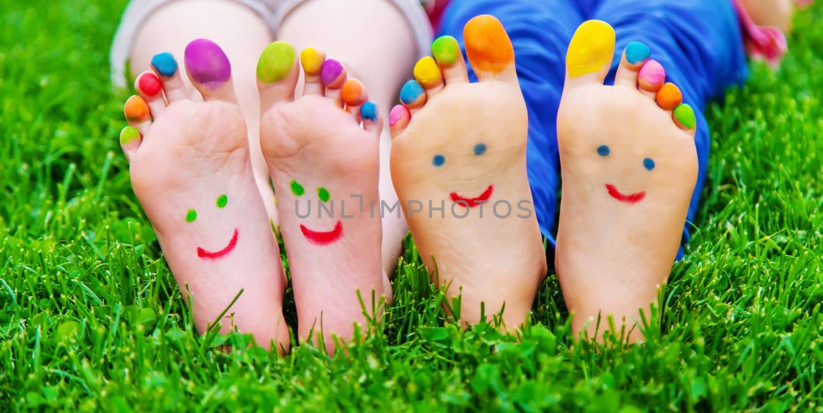 Children's feet with a pattern of paints smile on the green grass. Selective focus.child