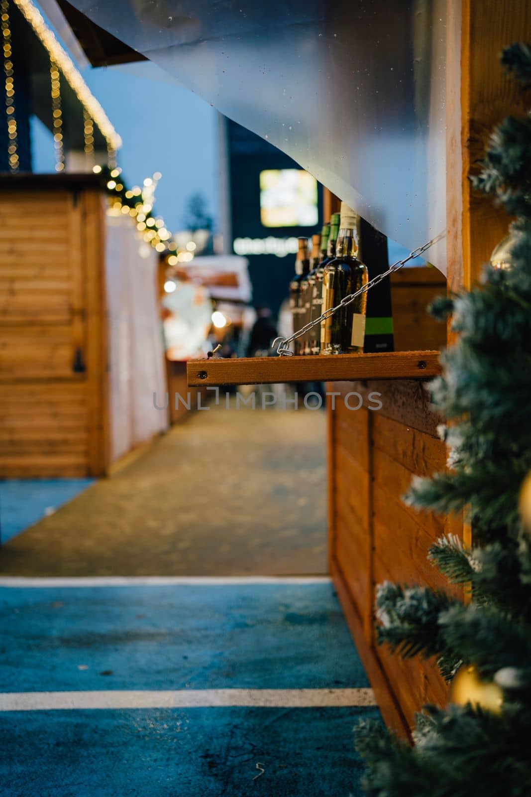 Christmas market on a rainy day. Some wine bottles being sold on a wooden shed.