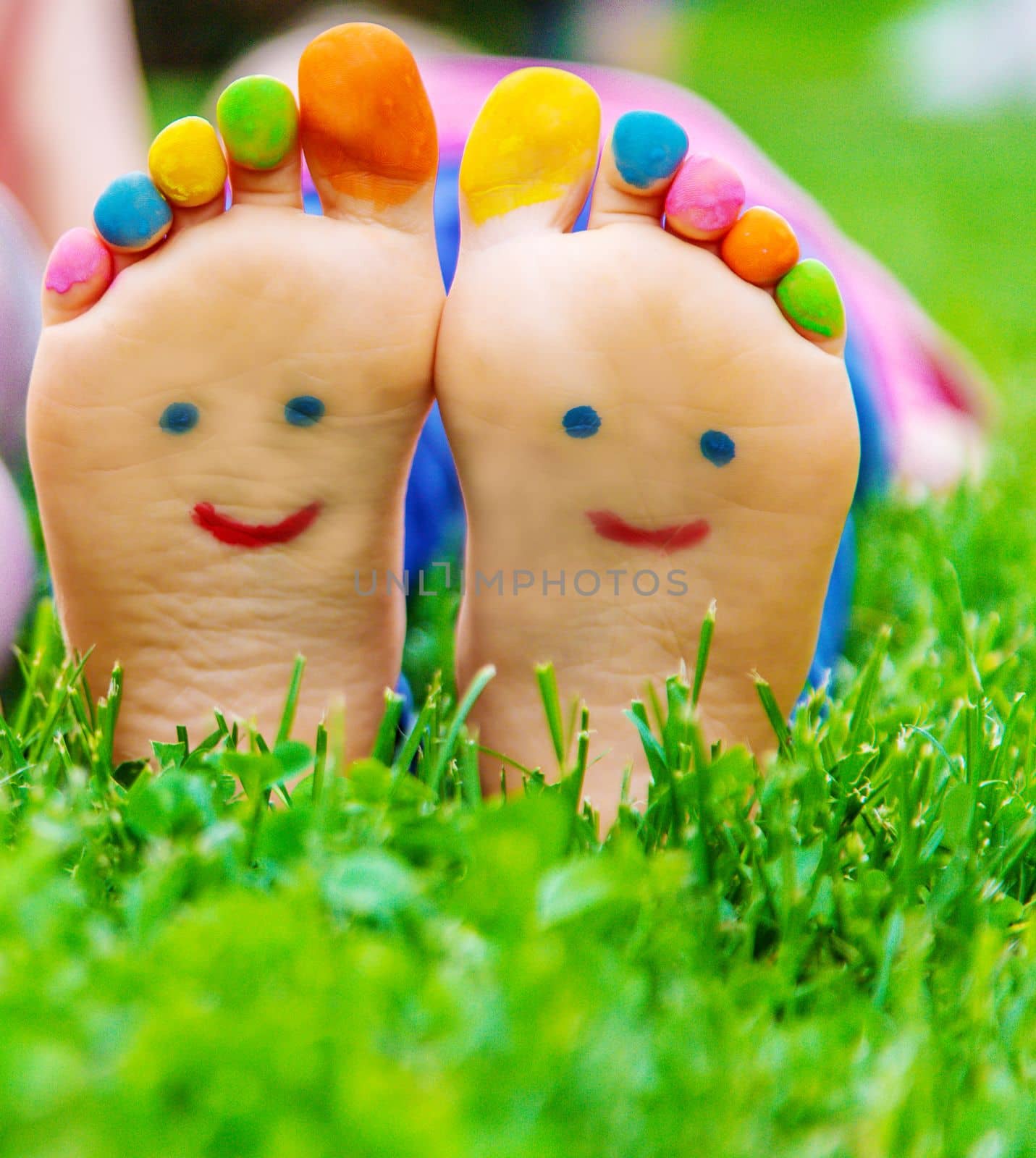 Children's feet with a pattern of paints smile on the green grass. Selective focus.child