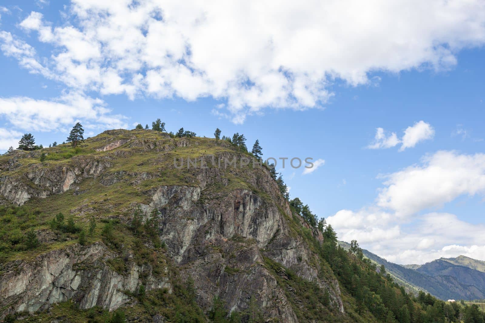 A large mountain with a sheer cliff close-up against the sky.  by AnatoliiFoto