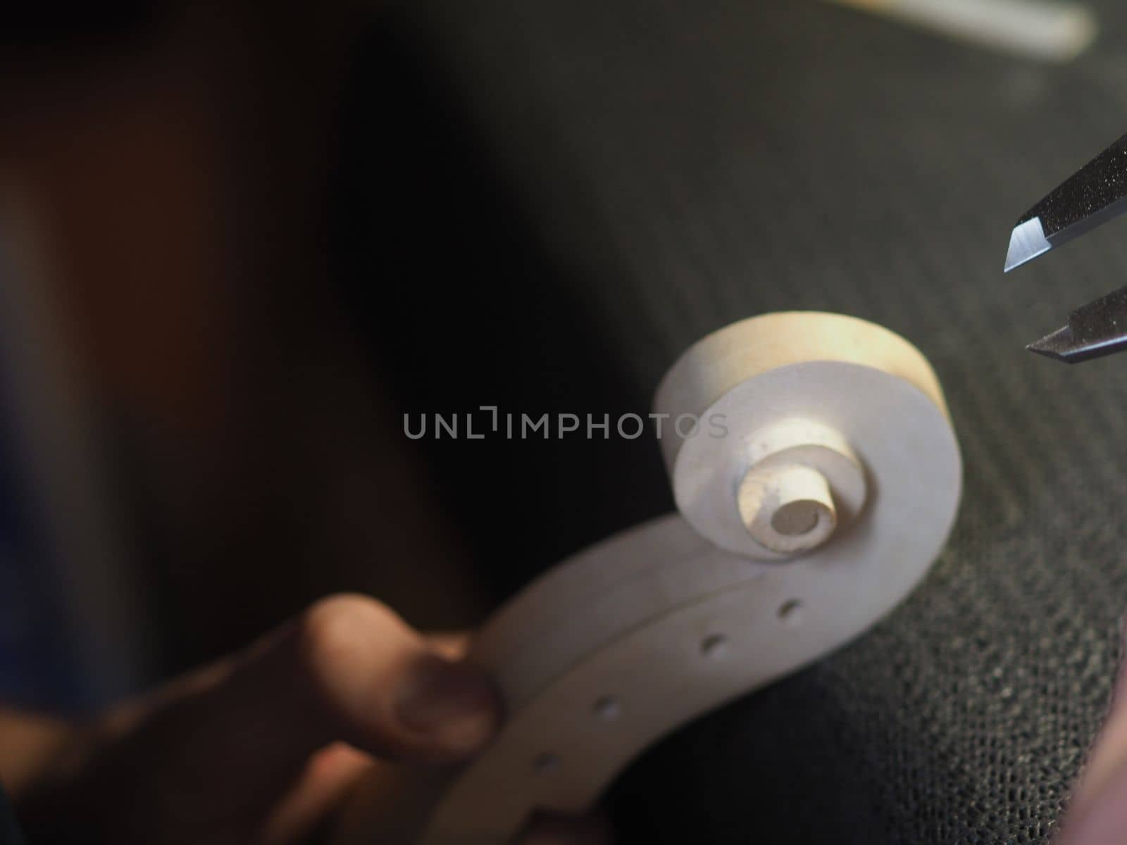 violin maker using a meter to shape and accurate measure fiddle scroll