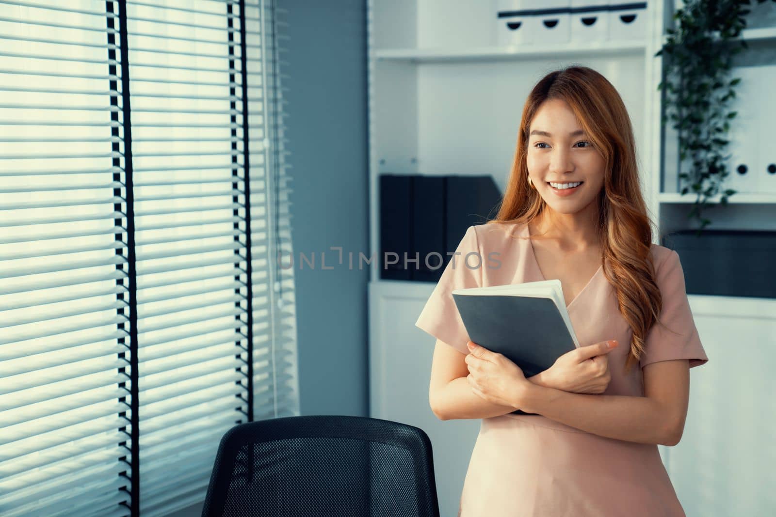 Young competent office lady, intern, secretary holding a log in office room. Concept of various career for office working. Concept of diverse office careers.