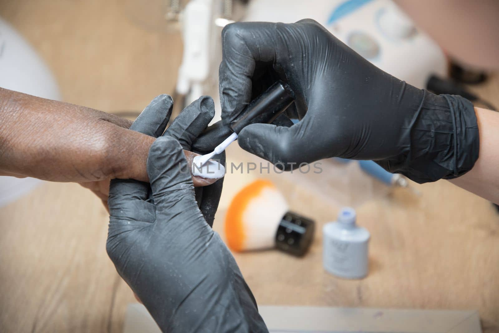 Manicurist covers the nails of a dark-skinned girl with blue gel polish in a beauty salon, High quality photo