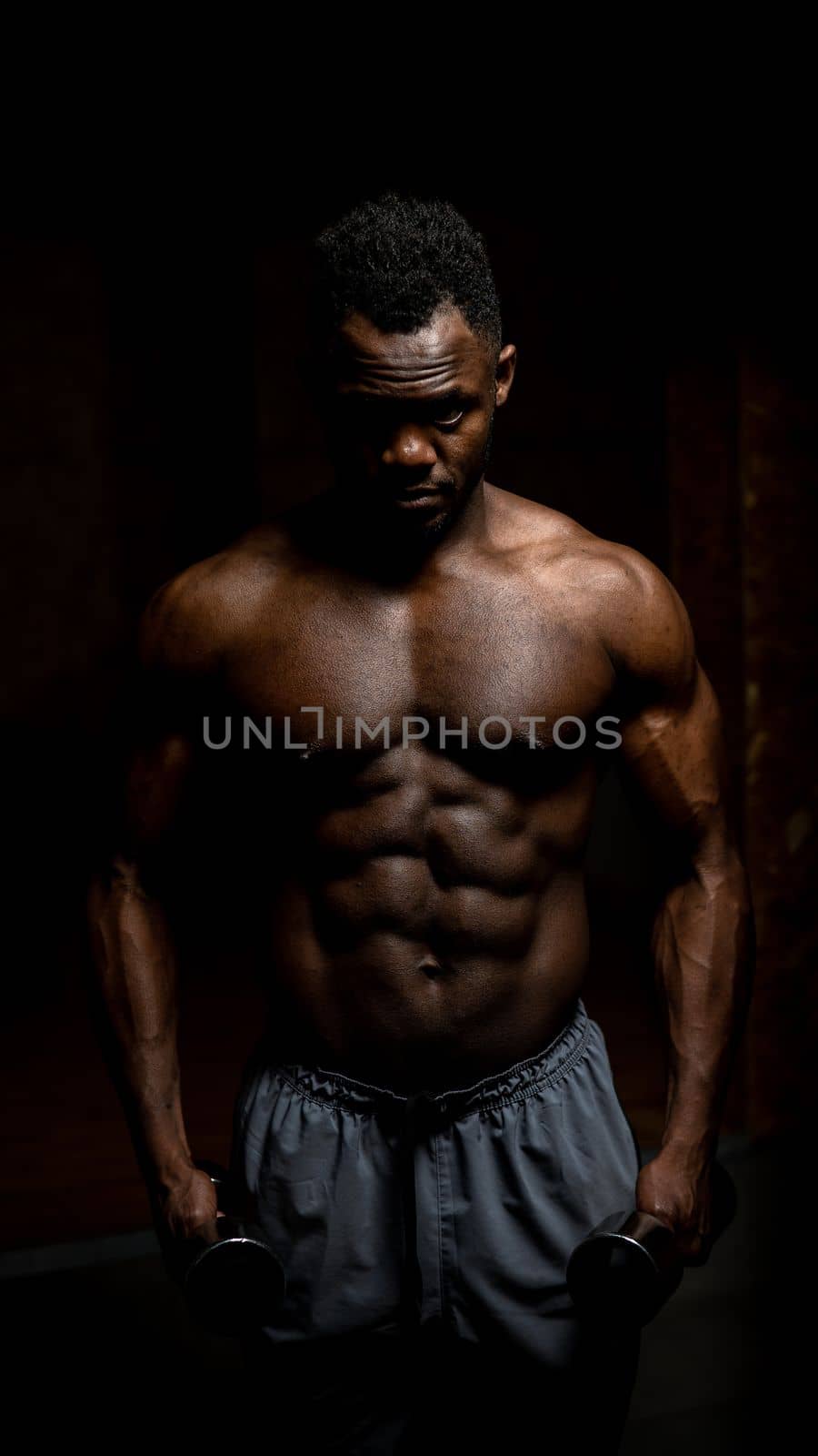 Muscular dark-skinned man doing an exercise with dumbbells