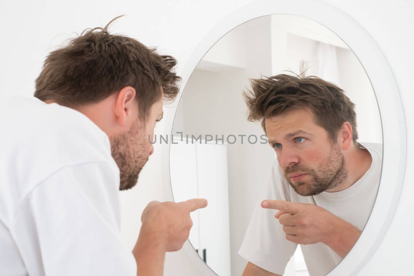 Caucasian mature man trying to encourage himself showing thumb up looking in mirror on the morning.