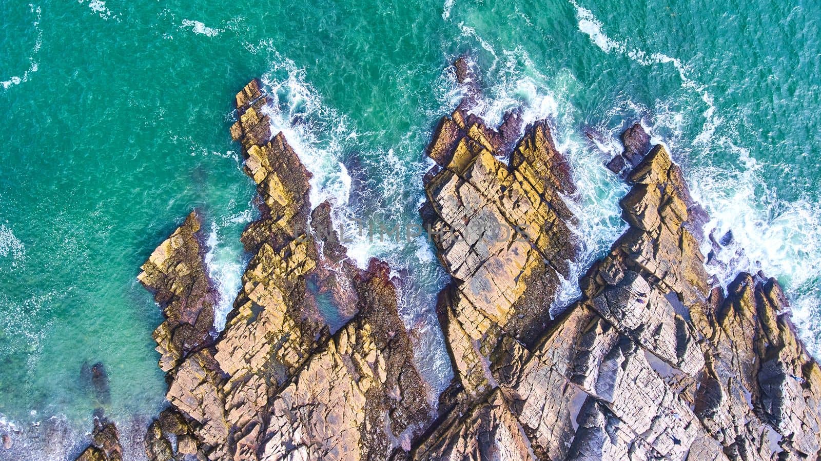 Image of Aerial looking down on patch of rocky coasts in Maine with crashing waves