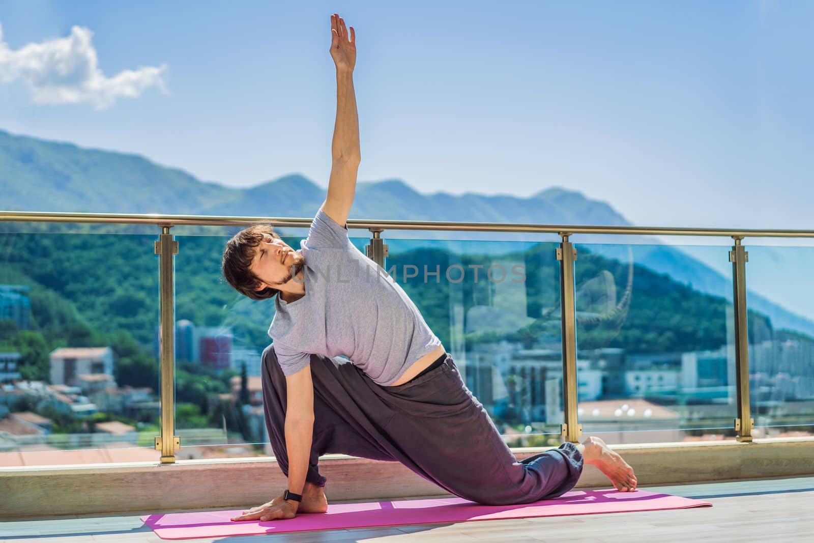 Man doing yoga outdoors on a rooftop terrace.