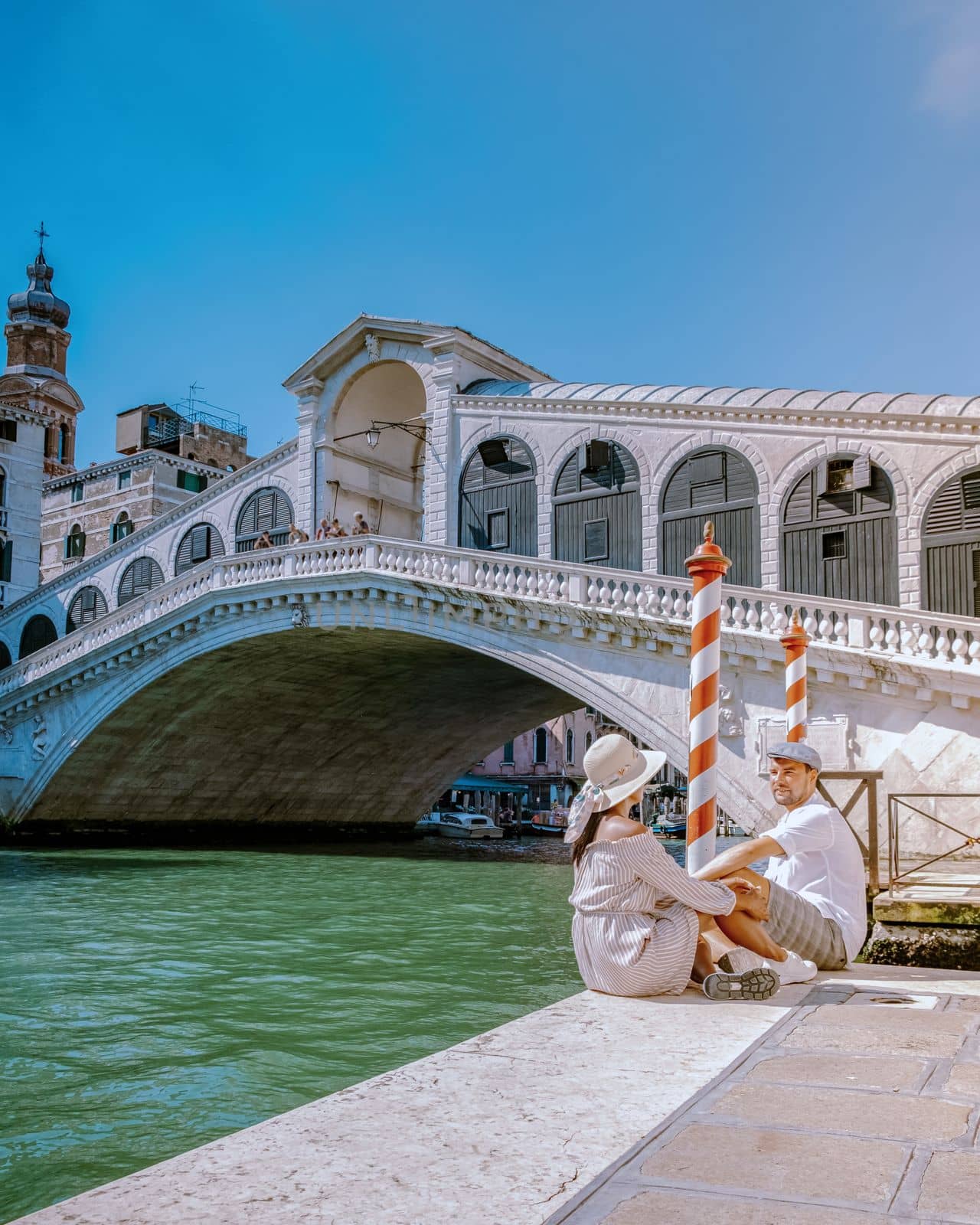 Venice Italy couple men and woman on a city trip to Venice, men and woman at the waterfront looking at the famous Rialto bridge in Venice Italy. Europe