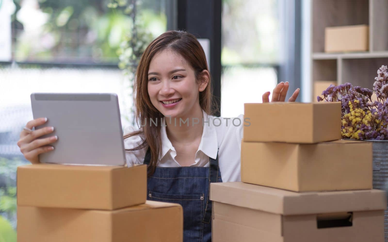 A portrait of a small startup, an SME owner, an Asian female entrepreneur checking orders to arrange the produce before packing the products in the inner boxes with the customers. Freelance concepts..