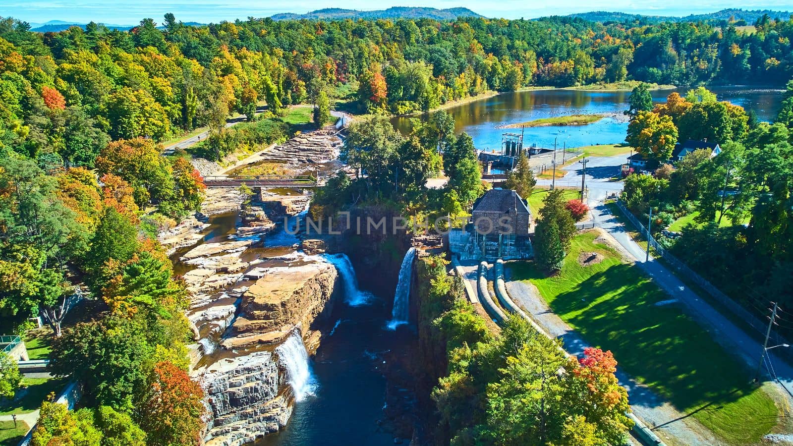 Image of Large canyon with many waterfalls, Hydroelectric power plant, and nearby lake from drone