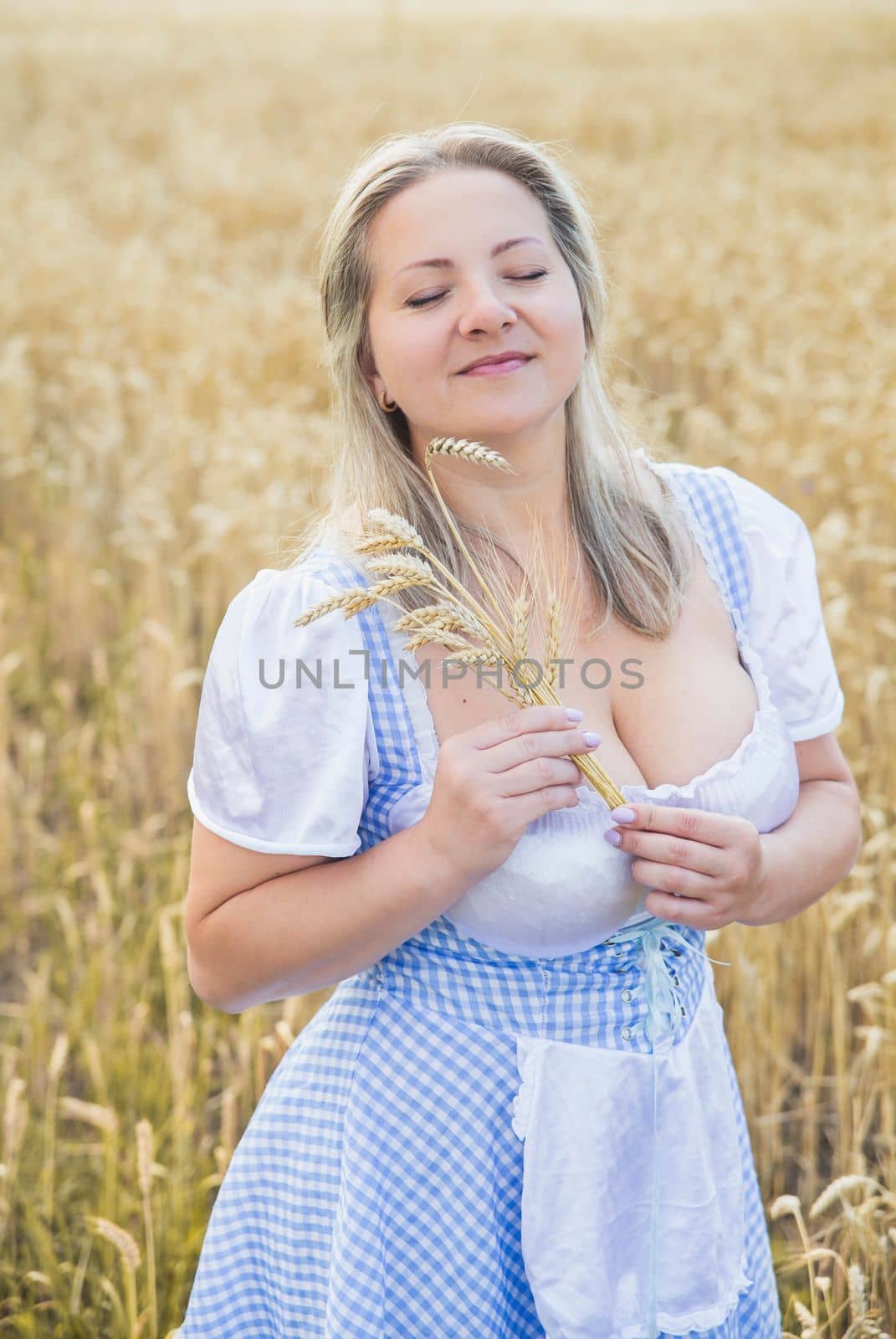 beautiful blonde holds spikelets in a wheat field.