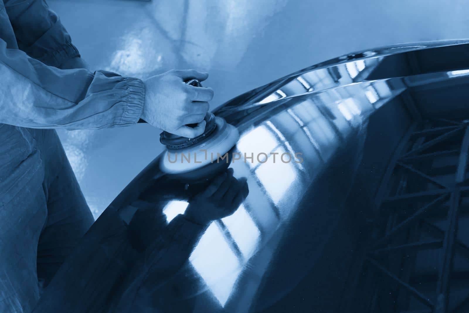 Close-up of hands worker using polisher to polish a gray car body in the workshop, Auto Mechanic Polishing Car by Mariakray