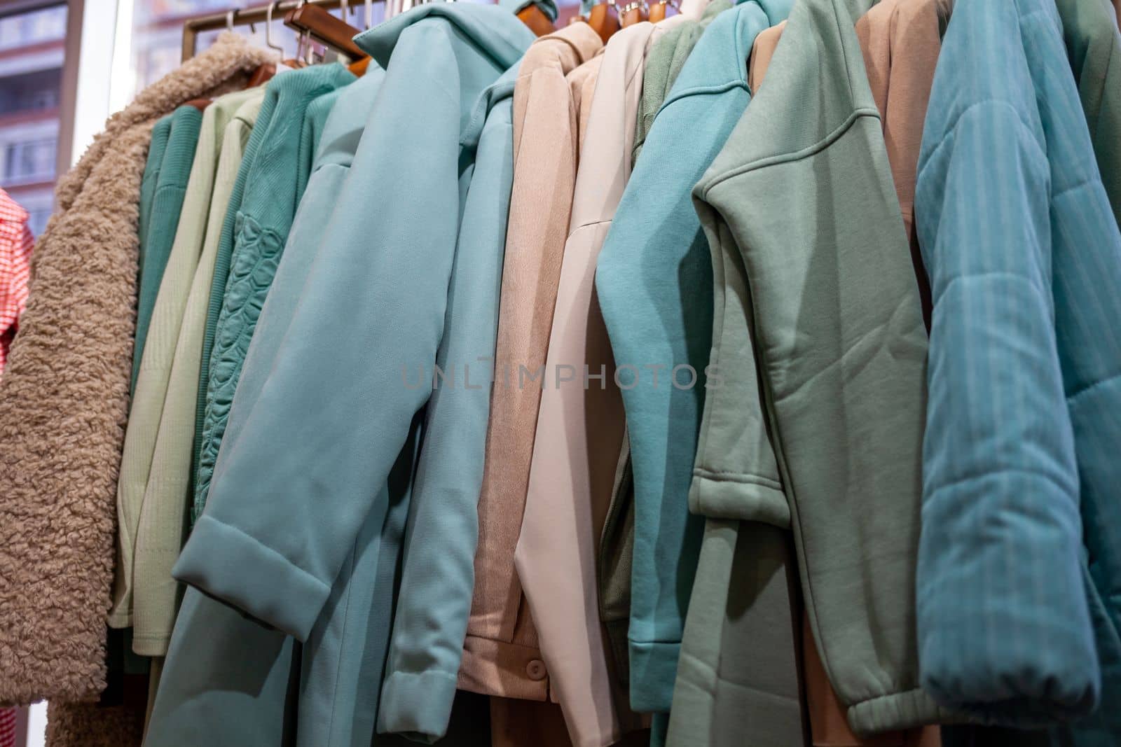 Colorful women's dresses, jackets, trousers and other clothes on hangers in a retail store. The concept of fashion and shopping. Women's clothing boutique.