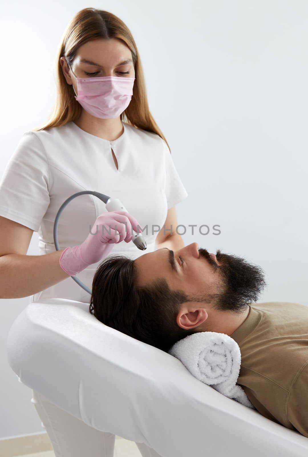 Doctor female dermatologist trichologist makes a procedure to stimulate hair growth to a patient man. Laser treatment of alopecia and hair loss
