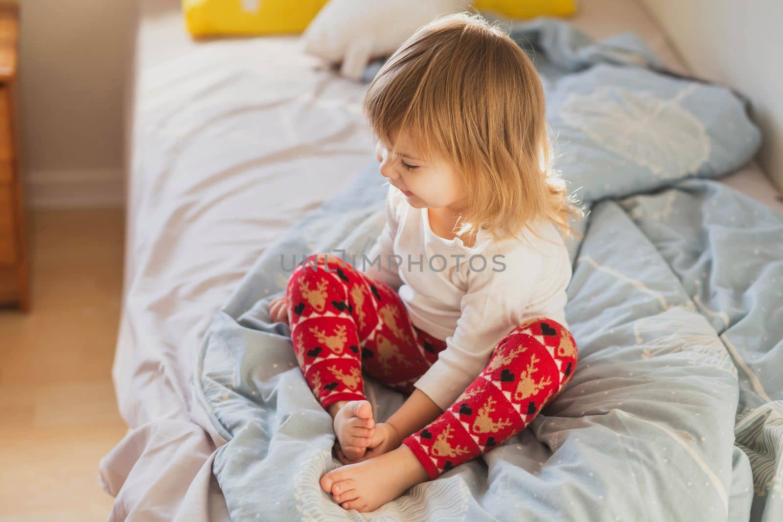 charming beautiful baby in festive leggings on the bed.