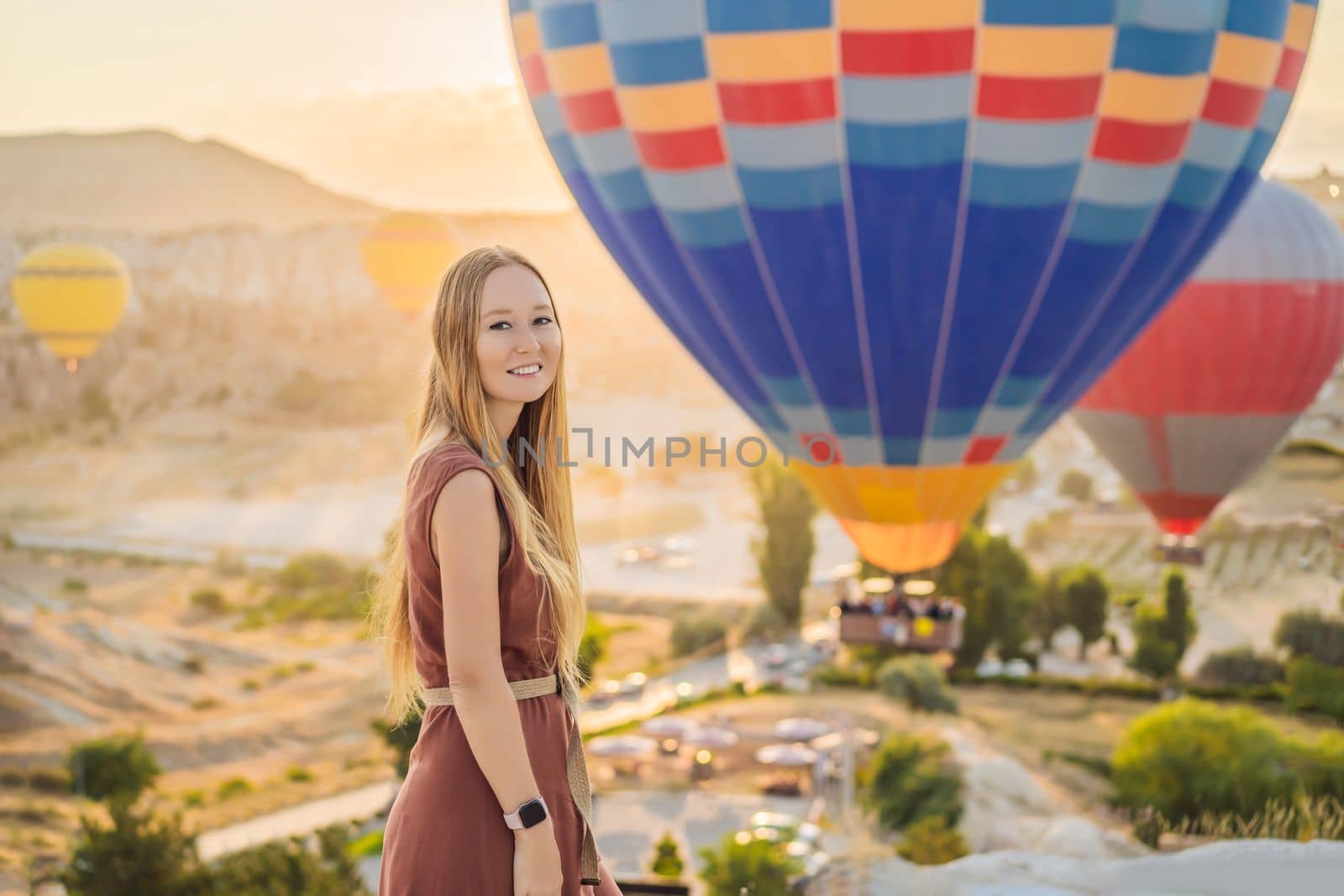 Tourist woman looking at hot air balloons in Cappadocia, Turkey. Happy Travel in Turkey concept. Woman on a mountain top enjoying wonderful view.