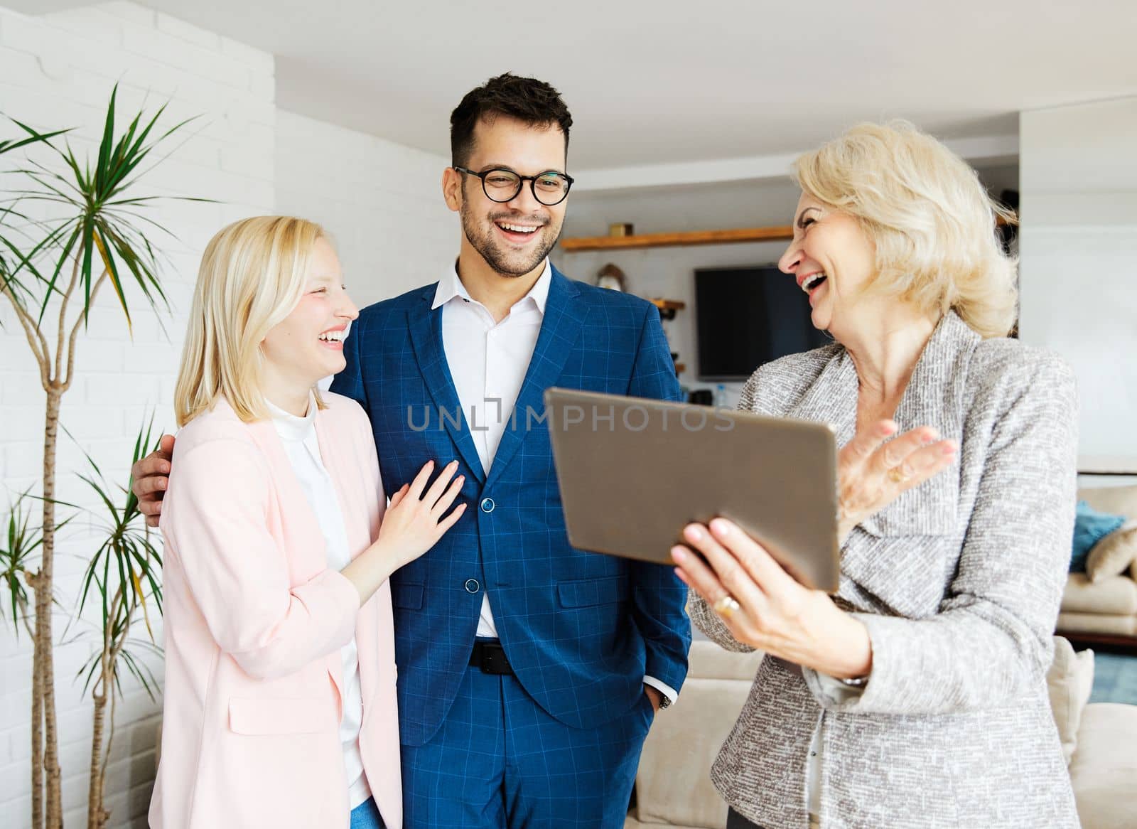 Young happy couple and an agent in a new property