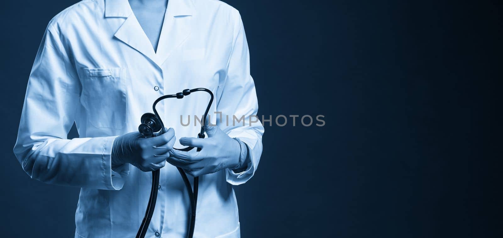 Young doctor with stethoscope against black background, cropped studio shot with copy space by Mariakray