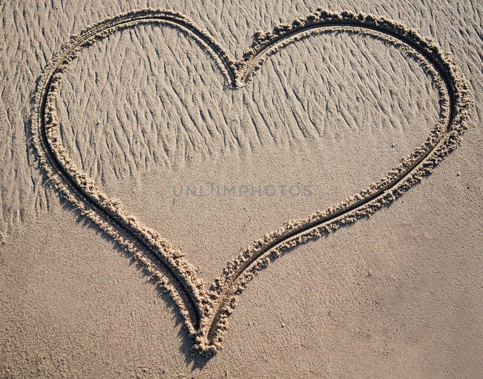 A big heart shape drawn in the sand with copy space.