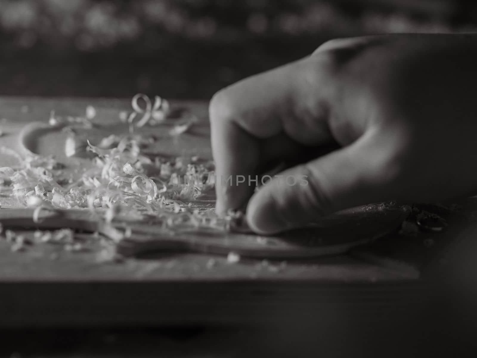 luthier working on raw wood violin plate with finger plane on the bench
