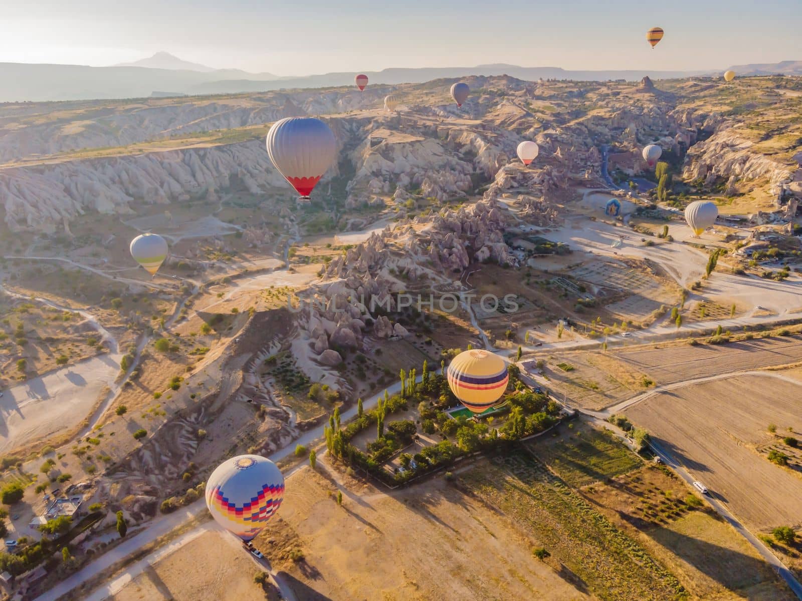 Colorful hot air balloons flying over at fairy chimneys valley in Nevsehir, Goreme, Cappadocia Turkey. Spectacular panoramic drone view of the underground city and ballooning tourism. High quality by galitskaya