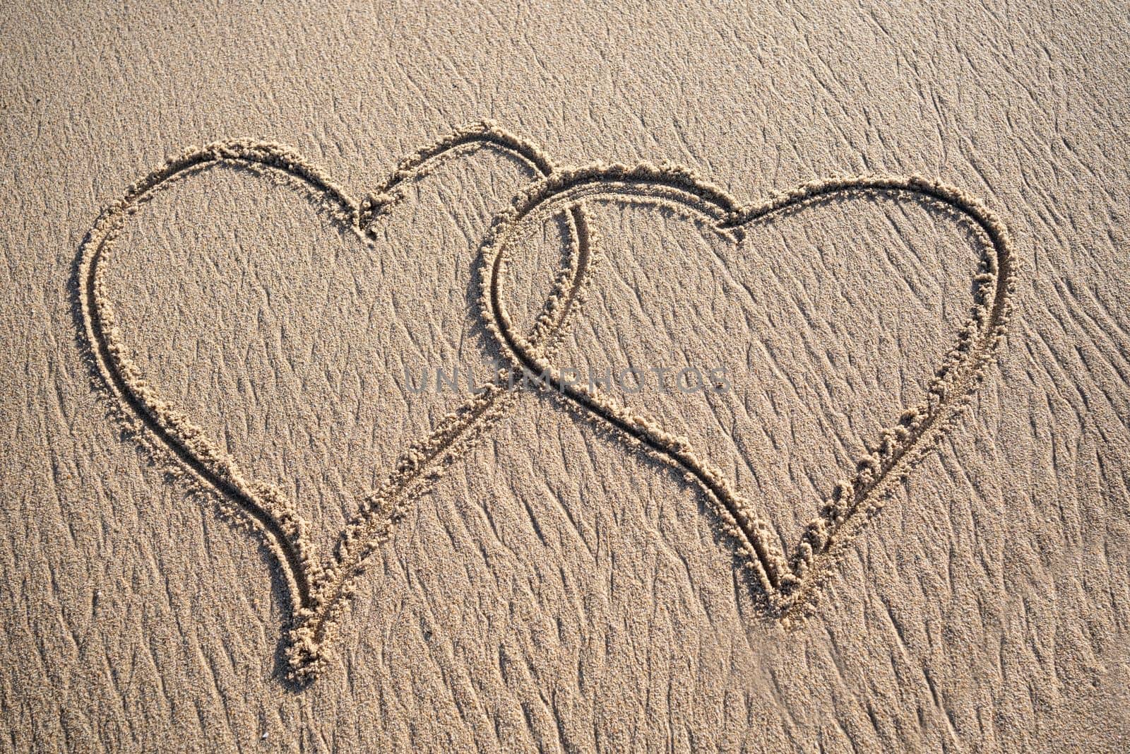 Two hearts drawn on a sandy beach by the sea. Sunset view. Love symbol.. by papatonic